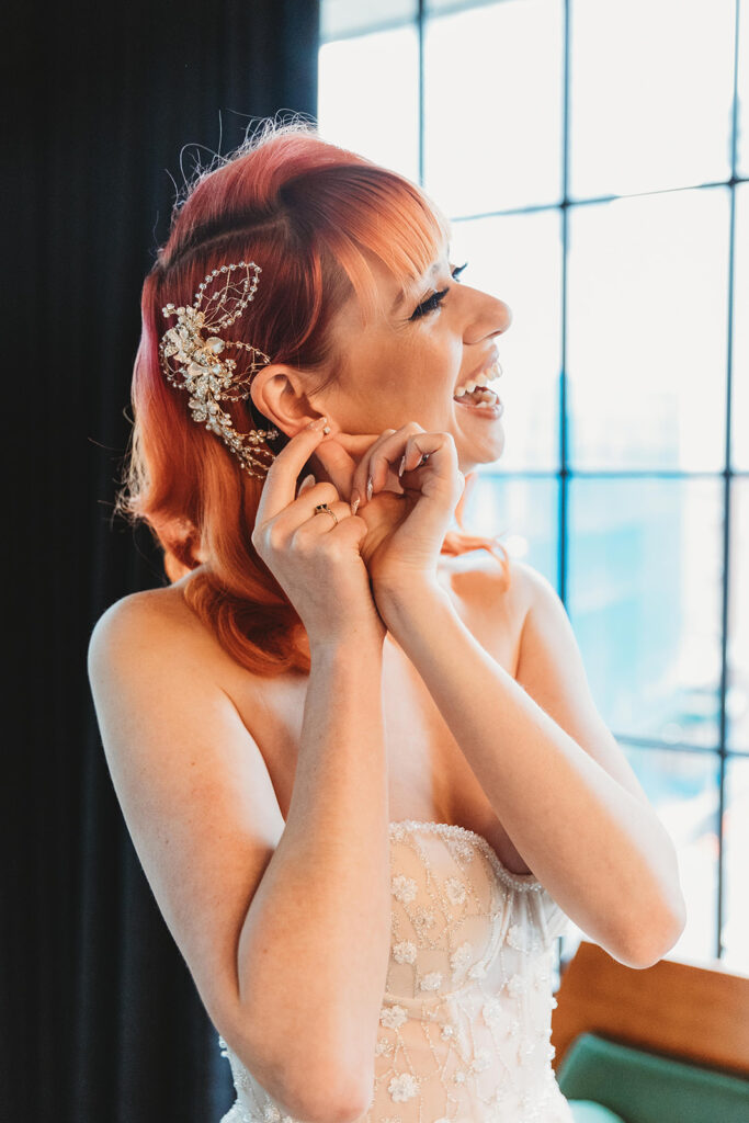 Close up photo of the bride in her dress putting her earrings in.