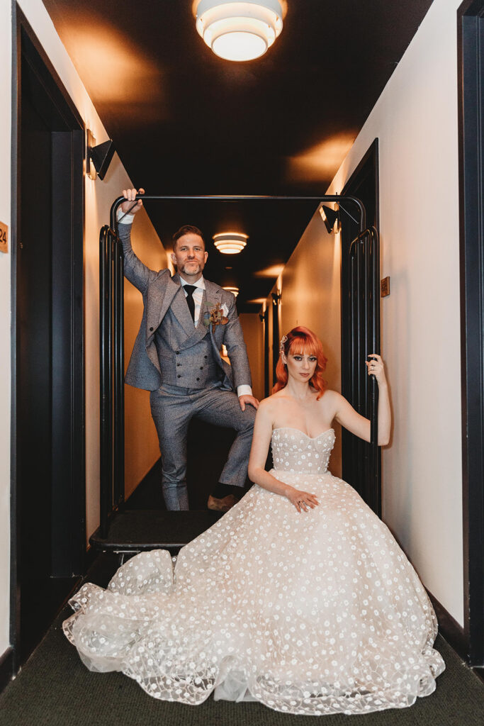 The bride and groom posed on a luggage cart in the hotel's hallway.