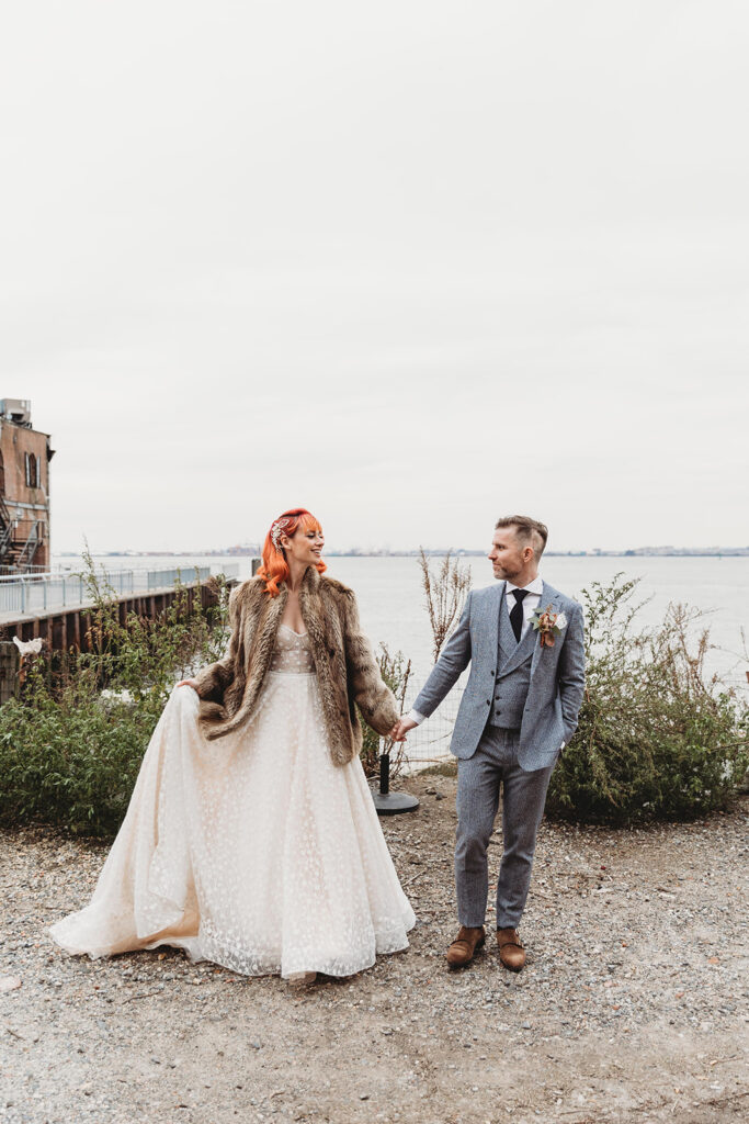 Bride and groom hold hands with Hudson River in the background