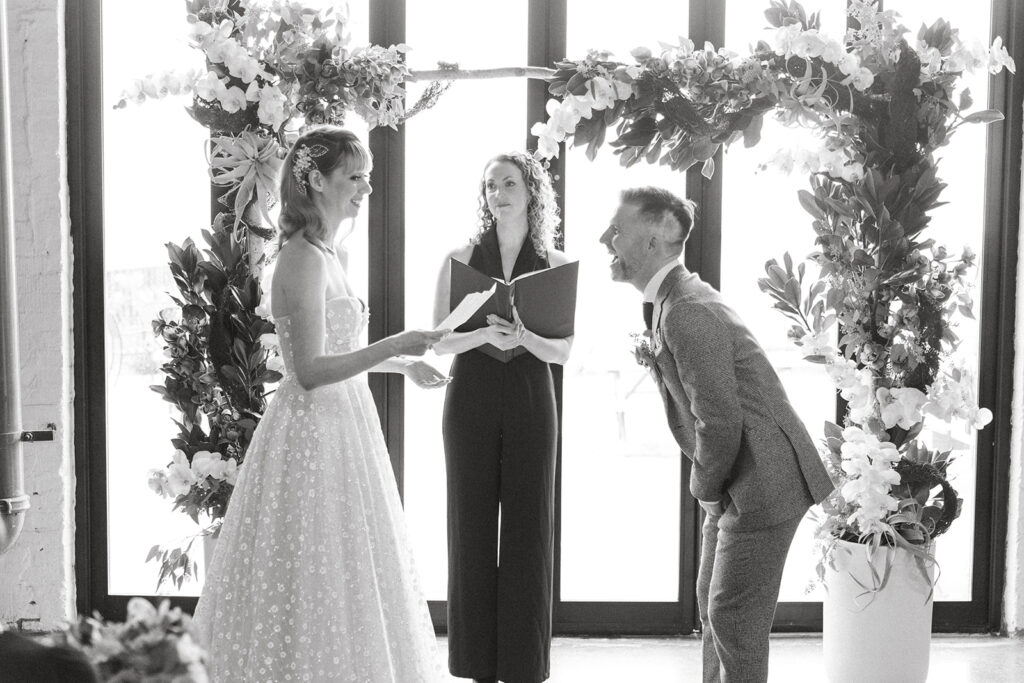 bride and groom reading vows and laughing big at each other
