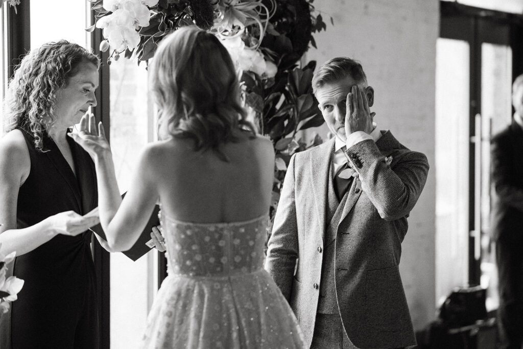 groom wipes his eyes during the ceremony at Strong Rope Brewery