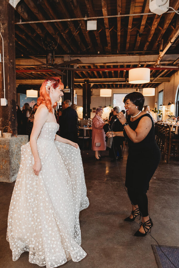 Bride and the singer of the evening having a moment together singing and laughing