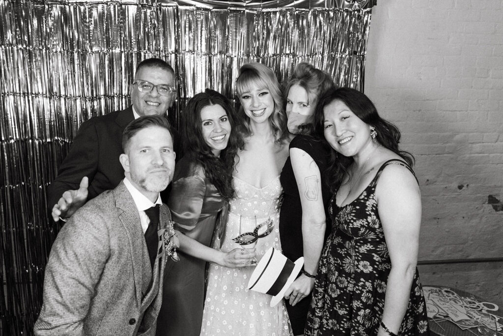 bride and groom pose with friends at the photobooth