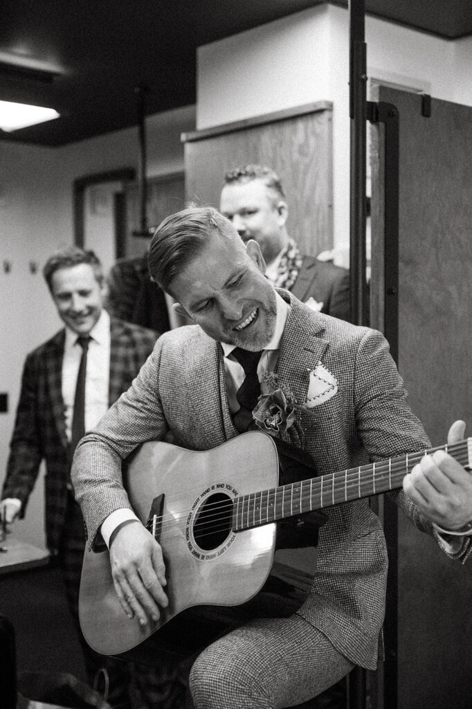 A black and white image of the groom playing the guitar and singing